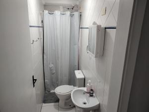 a white bathroom with a toilet and a sink at Apartamento com piscina! in Samaritá
