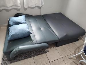 a black leather couch with two blue pillows on it at Apartamento com piscina! in Samaritá