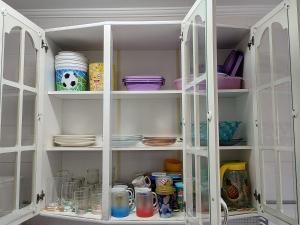 a white cabinet filled with dishes and plates at Apartamento com piscina! in Samaritá