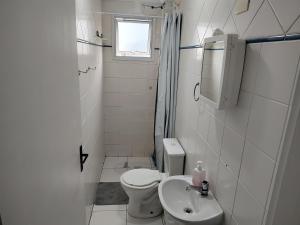 a white bathroom with a toilet and a sink at Apartamento com piscina! in Samaritá