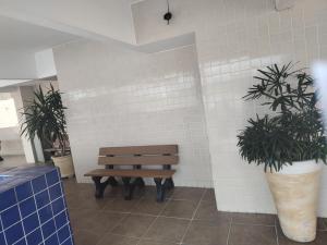 a bench in a room with two potted plants at Apartamento com piscina! in Samaritá
