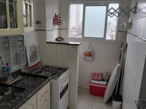 a small kitchen with a stove and a sink at Apartamento com piscina! in Samaritá