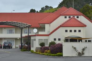 a house with a red roof and a parking lot at Brougham Heights Motel in New Plymouth