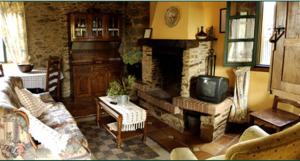 a living room with a fireplace and a tv at Casa Farruco in Beigondo