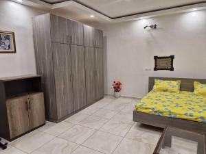 Cocody saint Jean في أبيدجان: غرفة نوم مع سرير مع أغطية صفراء وخزانة