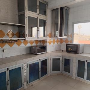 eine Küche mit weißen Schränken und einer Mikrowelle in der Unterkunft Zen Horizon in Grand Médina