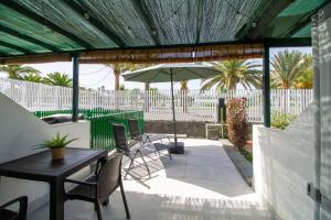 un patio con tavolo, sedie e ombrellone di El Nidito a Maspalomas