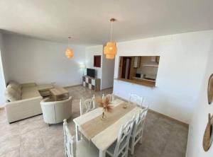 a dining room and living room with a table and chairs at Apartamento Infantes Playa in Sanlúcar de Barrameda +9 photos