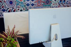 a white computer monitor sitting next to a potted plant at Anchor Boutique House in Patong Beach