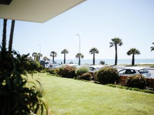 a view of a parking lot with palm trees and cars at Mouille Point Villa Capri in Cape Town