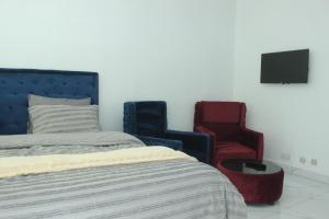 a bedroom with two chairs and a bed and a tv at Blantyre Airport Lodge in Chileka +2 photos
