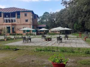 a patio with tables and chairs and umbrellas at West View Hotel in Rānīkhet