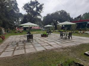 a patio with tables and chairs and umbrellas at West View Hotel in Rānīkhet