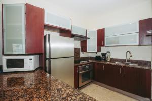 eine Küche mit einem Kühlschrank aus Edelstahl und einer Mikrowelle in der Unterkunft EL FARO 204 SURF two bedrooms apartment ocean front in Playa del Carmen