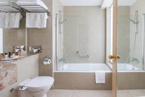 a bathroom with a tub and a toilet and a shower at Golden Bay Beach Hotel in Larnaca