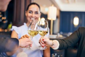 two people holding glasses of white wine at Hotel Atlantic Hamburg, Autograph Collection in Hamburg