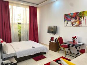 a bedroom with a bed and a table and a tv at Hotel Etoile Du Stade in Yamoussoukro