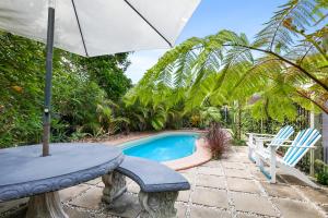 een patio met een tafel, een parasol en een zwembad bij Beachcomber Peregian Beach in Peregian Beach
