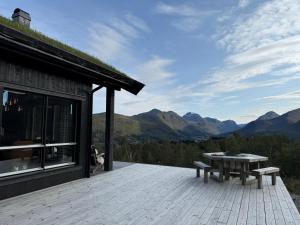 a wooden deck with a table and bench on a building at Roaldsida Retreat in Stranda