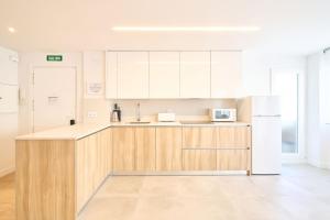 a kitchen with white cabinets and a white refrigerator at La brisa del Jerte by keyhom in Plasencia