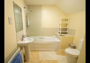 a bathroom with a tub and a sink and a toilet at Dune Horizon - Camber Sands, East Sussex in Camber