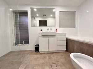 a bathroom with a sink and a tub and a toilet at Oceanview Sunset Villa Hallett Cove 3BR 2Bath Large Deck Free Parking in Halletts Cove