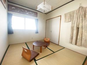 a room with a chair and a table and a window at Tasogare Apartment 201 in Hakodate