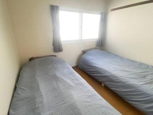 two beds in a small room with a window at Tasogare Apartment 201 in Hakodate