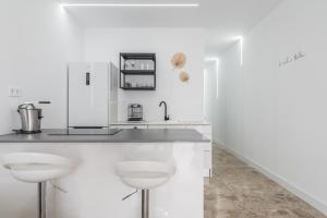 a white kitchen with a counter and stools at Canteras 1º Linea de Playa in Las Palmas de Gran Canaria +66 photos