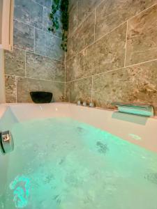 a bath tub filled with water in a bathroom at L'Antique Plaza, Appartement atypique et unique avec balnéo, proche centre et plage in Le Portel