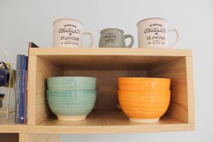 three bowls and cups on a wooden shelf at S’alba Noa in Quartu SantʼElena +47 photos