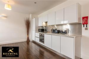 Il comprend une cuisine blanche avec des placards blancs et du parquet. dans l'établissement Sleeps 6 - Central - Free Secure Parking - 2 Bath, à Reading