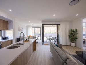 eine Küche und ein Wohnzimmer mit einer Couch und einem Tisch in der Unterkunft Brand New 4Bs Home near Shops and Park at Greenbank in Greenbank