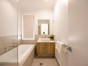 ein Badezimmer mit Badewanne, Waschbecken und Spiegel in der Unterkunft Brand New 4Bs Home near Shops and Park at Greenbank in Greenbank