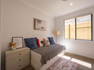 ein Schlafzimmer mit einem Bett mit einer Kommode und einem Fenster in der Unterkunft Brand New 4Bs Home near Shops and Park at Greenbank in Greenbank