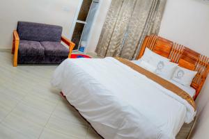 a bedroom with a large bed and a chair at BEZINDA LODGE in Dodoma