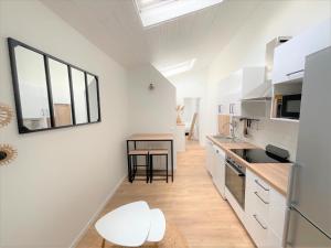 une cuisine avec des armoires blanches, une table et une fenêtre dans l'établissement T3 plein centre proche Versailles Saint Quentin en Yvelines, à Voisins-le-Bretonneux