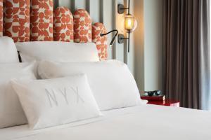 a bed with white sheets and a pillow with the word nav at NYX Hotel Rome by Leonardo Hotels in Rome