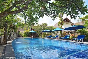 una piscina con sillas y sombrillas azules en Puri Dewa Bharata Hotel & Villas, en Legian