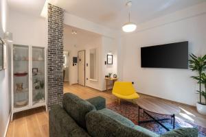 a living room with a couch and a tv on a wall at 1BR Stylish Apt 20 Minutes from Acropolis in Athens