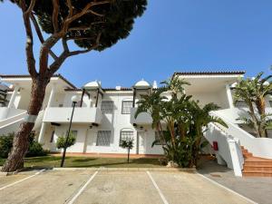 duży biały budynek z palmami na parkingu w obiekcie Apartamento Castillo de Mar w mieście Chiclana de la Frontera