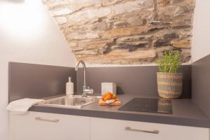a kitchen with a sink and a stone wall at Il Porticciolo by Rent All Como in Carate Urio +54 photos
