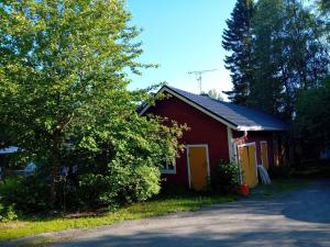 a red house with a tree next to a street at Huone Seesteisessä Mummolassa in Kalajoki