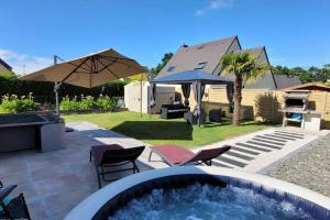 a backyard with a hot tub and chairs and an umbrella at Maison 4 chambres pour 8 personnes in Dol-de-Bretagne