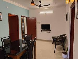 a living room with a table and chairs and a television at Padmam Service Apartments - 2BHK in Singānallūr
