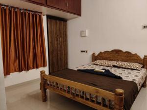 a bedroom with a wooden bed and a window at Padmam Service Apartments - 2BHK in Singānallūr