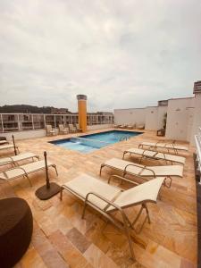 a pool on the roof of a building with lounge chairs at Apartamento morada morada do sol 208 in Ubatuba