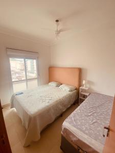 a bedroom with two beds and a window at Apartamento morada morada do sol 208 in Ubatuba