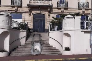 a building with stairs and a black door and a gate at Appt vue parc, avec terrasse in Châtel-Guyon