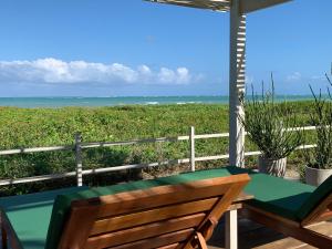 a table and chair on a porch with a view of the ocean at Abaetetuba Pousada in São Miguel dos Milagres